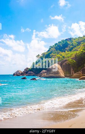 Vertical tropical landscape. Sea with a rocky shore and a mountain on a sunny day on a tropical island. Travel and tourism. Stock Photo