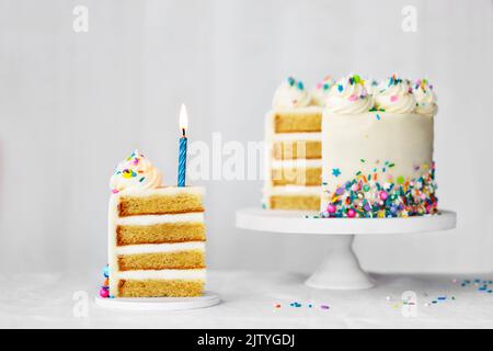 Sliced birthday cake with blue birthday candle and colorful sprinkles Stock Photo