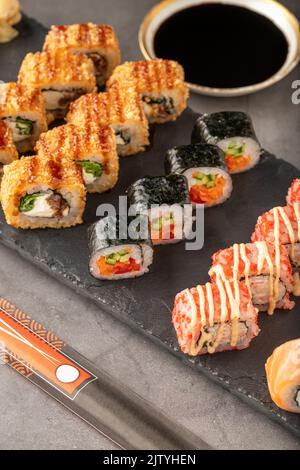 Sushi set of various products on a black stone plate. Blur background and selective focus Stock Photo