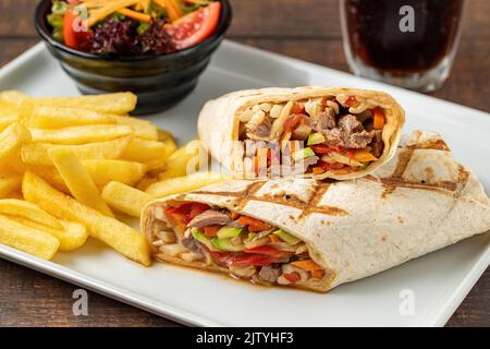 Meat wrap cut in half with french fries on dark stone table Stock Photo
