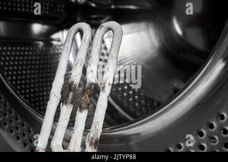 A burnt-out heating element of a washing machine against the background of a washing machine Stock Photo