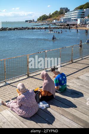 A Muslim family eats a picnic next to Three Shells Lagoon at Southend-on-Sea, Essex, UK. Stock Photo