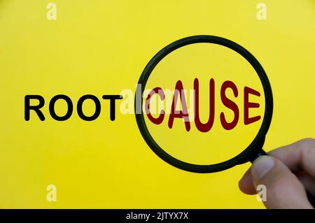 Close-up at root cause text through magnifying glass on yellow cover background. Root cause analysis concept. Stock Photo