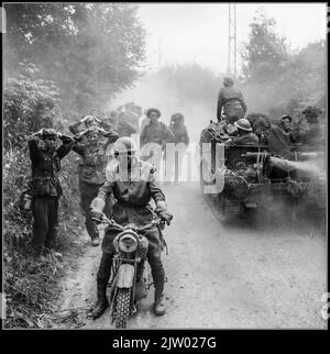 WW2 Normandy Invasion The British Army in the Normandy Campaign 1944 A mortar platoon carrier passes a group of Nazi German POWs prisoners with hands on heads, being escorted by a military policeman on a motorcycle, Caumont, 30 July 1944. Normandy France Date 1944 Stock Photo