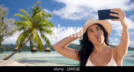 smiling woman in bikini taking selfie on beach Stock Photo