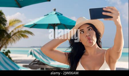 smiling woman in bikini taking selfie on beach Stock Photo