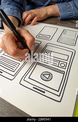 UI designer sketches the user interface of a web application for a mobile phone. A developer creates a prototype for a smartphone. Stock Photo
