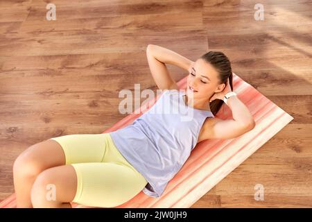 happy teenage girl exercising on yoga mat at home Stock Photo