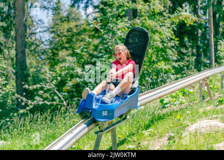 Teenage girl screams going down a mountain roller coaster Stock Photo