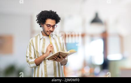 thinking young man with diary and pencil at office Stock Photo