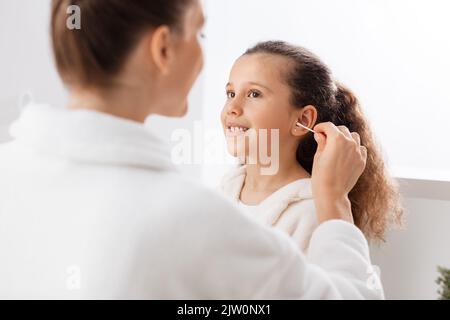 happy mother cleaning daughter's ear in bathroom Stock Photo