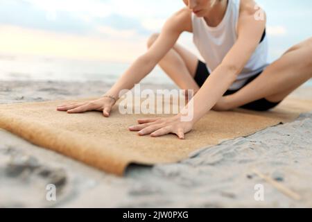 woman doing yoga stretching pose on beach Stock Photo