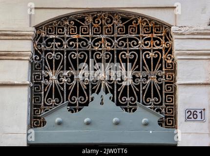 iron ornate grille on old weather beaten greek window for security, decorative wrought iron grille covering window on old weathered building in greece. Stock Photo