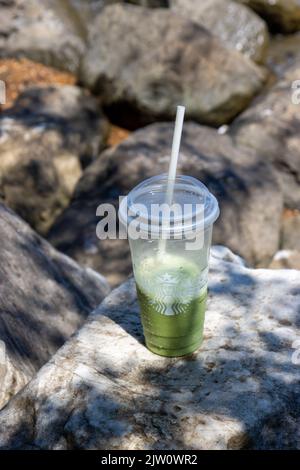 Starbucks Matcha Creme Frappuccino on a rock by the beach Stock Photo