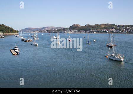 Conwy Quayside and Harbour in North Wales with boats at anchor on a calm early summer morning with Deganwy and the Great Orme in the background Stock Photo