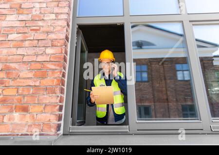 builder with clipboard and calling on smartphone Stock Photo