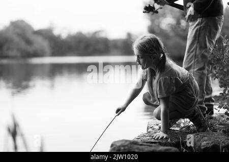 Young girl pushing her net in the water to try and catch something in the water. Stock Photo