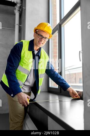 male builder with ruler measuring window sill Stock Photo