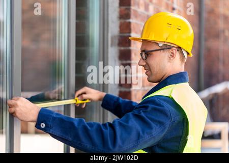 male builder with ruler measuring window Stock Photo