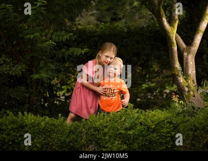 Young brother and sister posing outdoors without smiling. Stock Photo