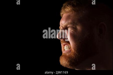Adult Caucasian male side head shot, showing teeth with an angry expression. Stock Photo