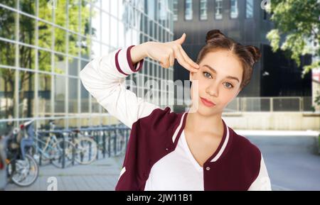 teenage girl making finger gun gesture in city Stock Photo