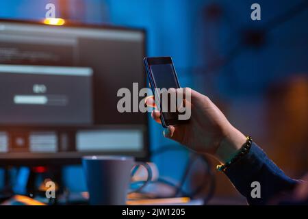 hacker with smartphone and computers in dark room Stock Photo