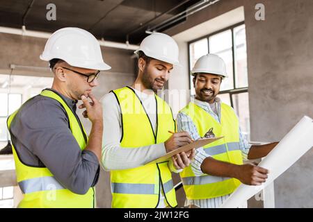 architects in helmets with blueprint at office Stock Photo