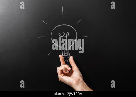 close up of hand holding lightbulb chalk drawing Stock Photo