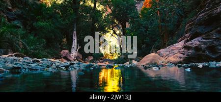 A valley surrounded by trees, rocks and a river. Stock Photo