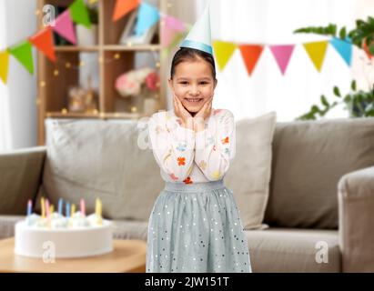 smiling little girl in birthday party hat at home Stock Photo