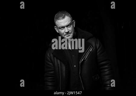 Middle-aged male looking into camera with a pose, studio light used. Stock Photo