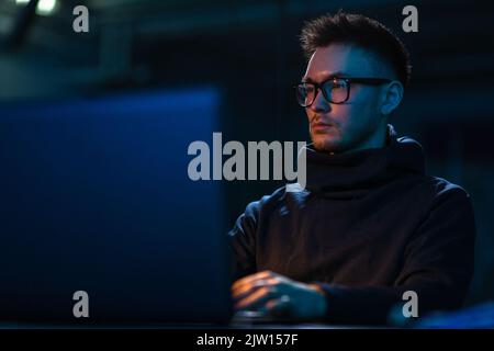 young man in glasses with laptop in dark room Stock Photo