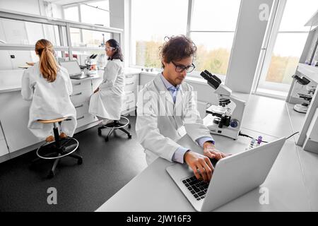 scientists with microscopes working in laboratory Stock Photo