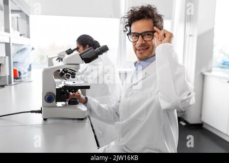 scientist with microscope working in laboratory Stock Photo