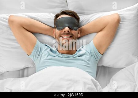 happy man in sleeping eye mask lying in bed Stock Photo