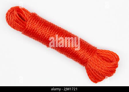 A coil of rope. Isolated. Large spool of red plastic cord on a white background. A long coil of kapron textured red cable. Durable nylon wire. Stock Photo