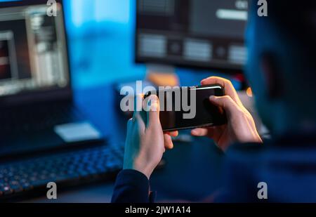 hacker with smartphone and computers in dark room Stock Photo