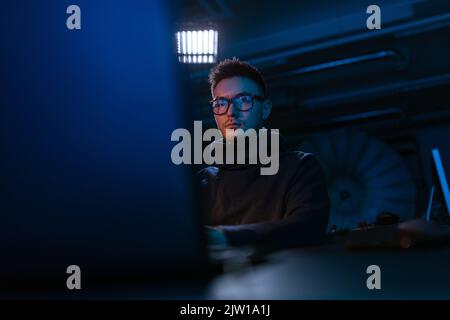 young man in glasses with laptop in dark room Stock Photo