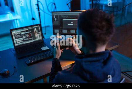 hacker with smartphone and computers in dark room Stock Photo - Alamy