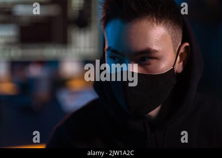 hacker wearing mask with computers in dark room Stock Photo