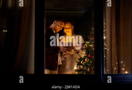 happy couple opening christmas gift at home Stock Photo