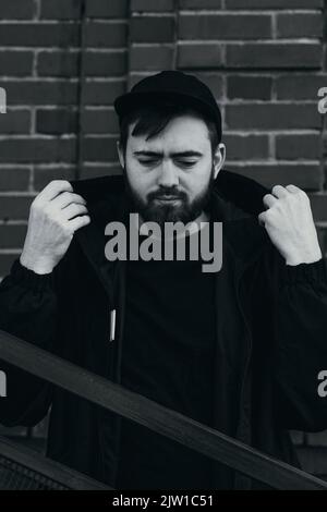 young man stands near a brick wall, black and white photo Stock Photo