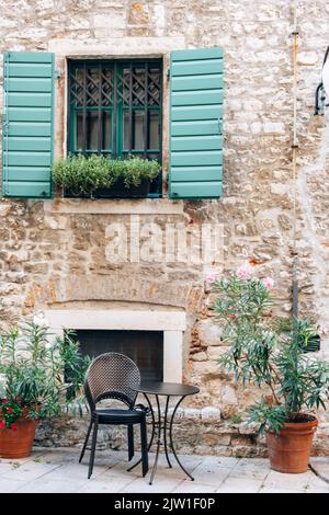 Window with green shutters and table of the street cafe in Sibenik, Croatia Stock Photo