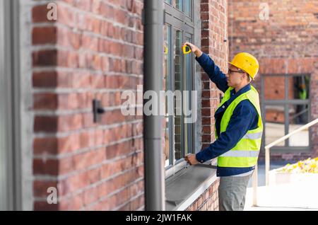 male builder with ruler measuring window Stock Photo