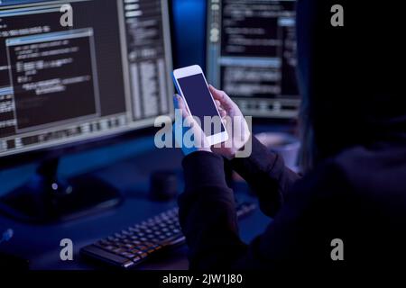 hacker with smartphone and computers in dark room Stock Photo