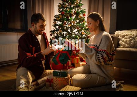 happy couple opening christmas gifts at home Stock Photo