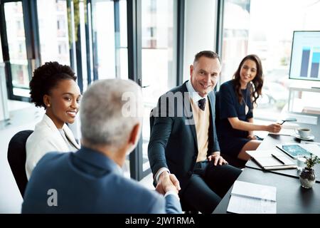 Excellent work. two businessmen shaking hands during a boardroom meeting. Stock Photo