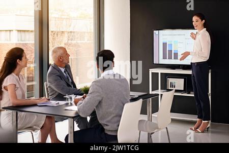 Making an impact with her business presentation. a young businesswoman delivering a presentation in a boardroom. Stock Photo