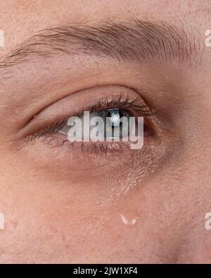 eye with a tear flowing down a woman cheek. Stock Photo